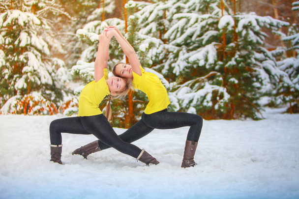 két gyönyörű nők csinál jóga kint a hóban  - Fotó, kép