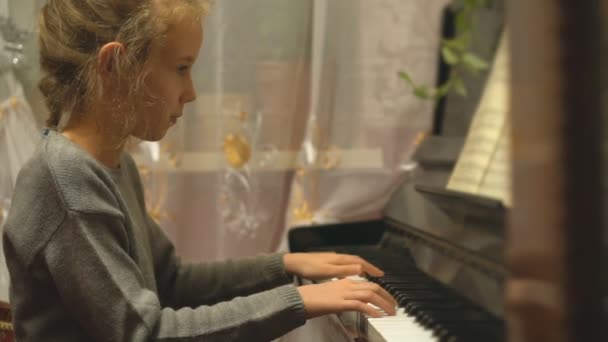 Całkiem mała dziewczynka uczy się grać na pianinie. - Materiał filmowy, wideo