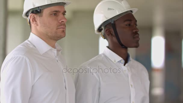 Two businessman looking at camera inside construction site - Footage, Video