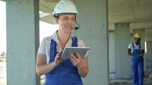 Female and fro-american men are constructors considered building plan on a tablet - Footage, Video