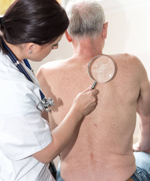Женщина-врач проверяет кожу пожилого пациента
 - Фото, изображение