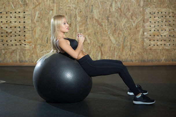beautiful young blond girl of European appearance doing exercise in the gym with a large rubber ball - Foto, Imagem