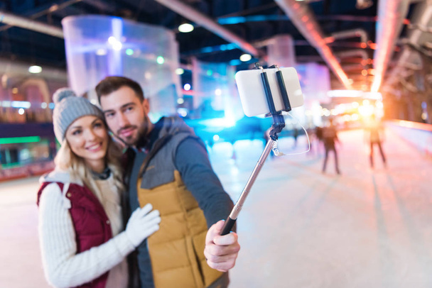 スケート リンク上のスマート フォンを持つ幸せな若いカップル撮影 selfie の選択と集中 - 写真・画像