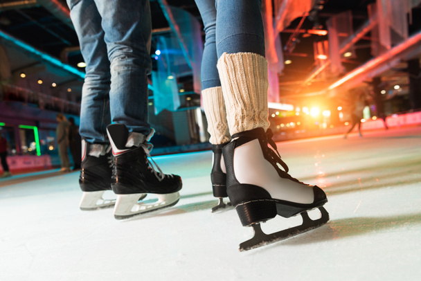 cropped shot of couple in skates ice skating on rink - 写真・画像