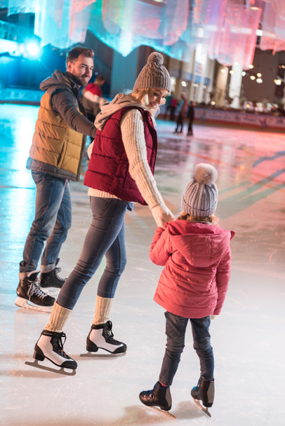 belle jeune famille heureuse tenant la main sur la patinoire
 - Photo, image