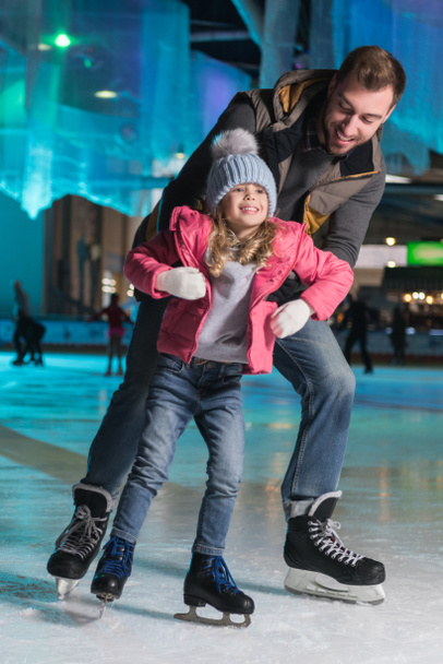 feliz padre abrazando adorable pequeña hija en pista de patinaje
 - Foto, Imagen