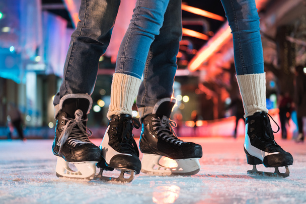 primer plano vista parcial de pareja joven en patines patinaje sobre hielo en pista de patinaje
 - Foto, Imagen