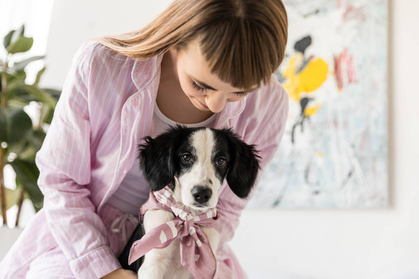 portrait of woman in pajamas and cute little puppy in morning at home - Photo, Image