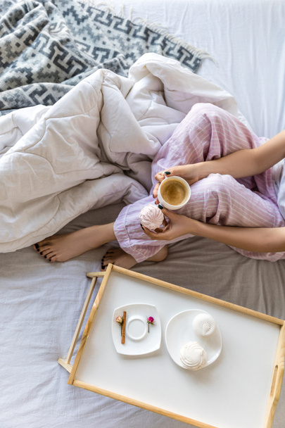 vista aérea de la mujer con taza de café y zephyr en las manos descansando en la cama
 - Foto, Imagen