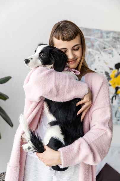 Portret van lachende vrouw knuffelen zwart-witte pup - Foto, afbeelding