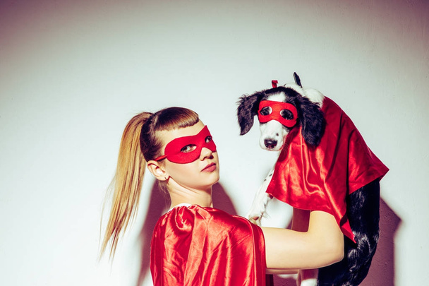 Zijaanzicht van de jonge vrouw en puppy in superheld kostuums - Foto, afbeelding