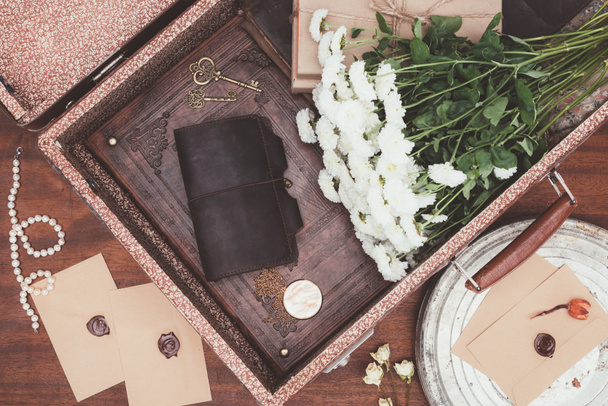 top view of opened vintage suitcase with objects over wooden background - Photo, Image