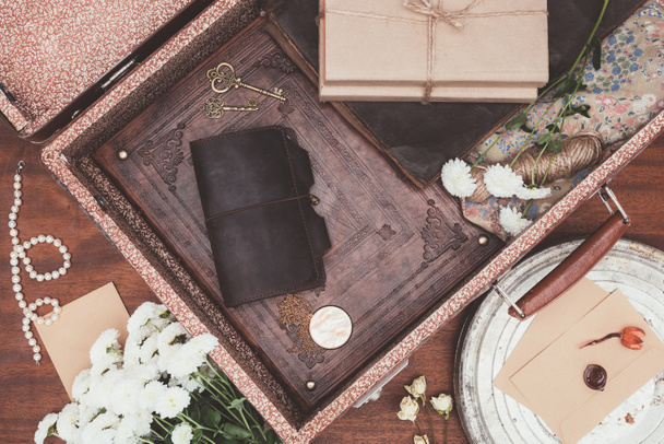 top view of opened vintage suitcase with objects over wooden background - Photo, Image
