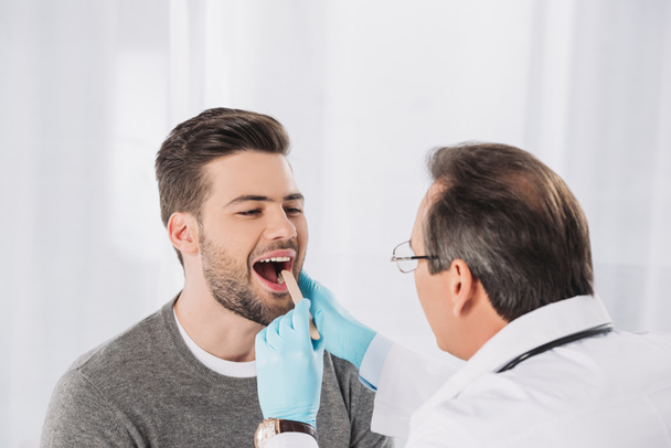 doctor examining patient throat in medical gloves - Fotoğraf, Görsel