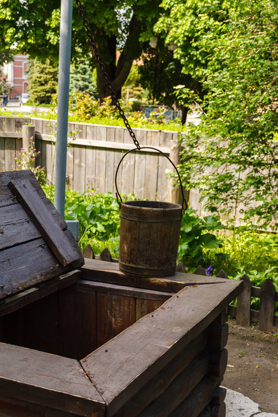 Un puits avec un cadre en bois, un mécanisme de levage de type grue et un godet en bois
 - Photo, image