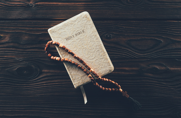 Widok z góry zamknięte Pismo Święte i różaniec z krzyża na drewnianym stole   - Zdjęcie, obraz