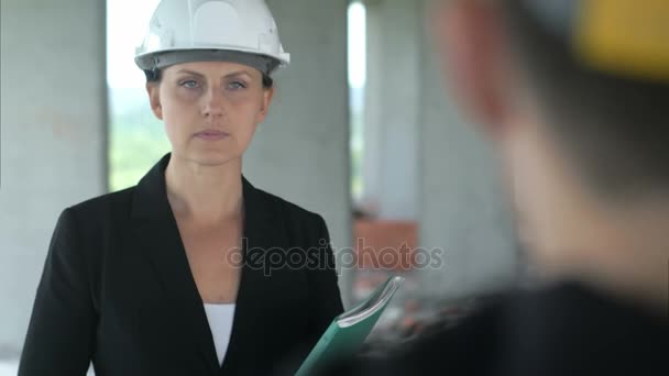 Una mujer de la construcción escuchando es colega en el edificio de oficinas
 - Imágenes, Vídeo