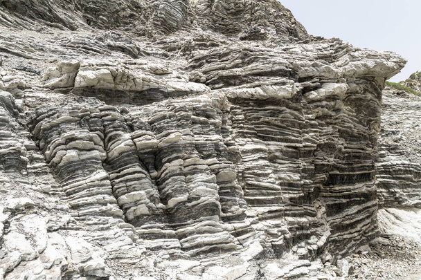 Kerroksellinen kivimuodostelma taittuu Välimeren saarella Kreetalla, Kreikassa
 - Valokuva, kuva