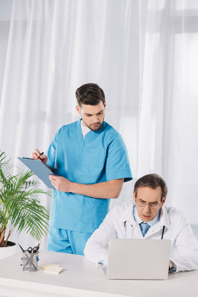 nurse and doctor looking at working laptop - Foto, Bild