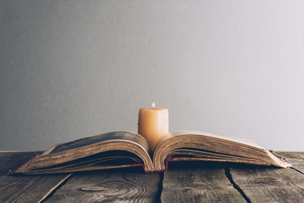 Open de Heilige Bijbel met kaars op houten tafel - Foto, afbeelding