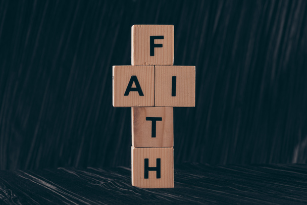黒いテーブルの上の単語の信仰と十字架の形の木製キューブ - 写真・画像