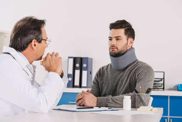 médico hablando con el paciente en soporte para el cuello
 - Foto, Imagen