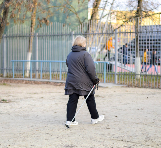 Older women walk around the park with ski poles. Life is retired. - Fotografie, Obrázek