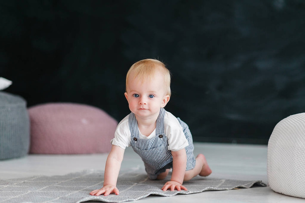 Kleines Baby krabbelt auf dem Boden vor schwarzem Hintergrund - Foto, Bild