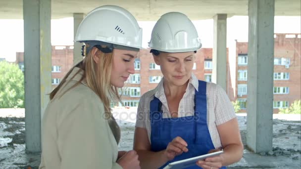 Vrouwelijke ingenieur en werknemer op de bouwplaats met plan op digitale tablet - Video