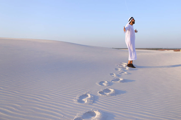 Radosny mężczyzn muzułmańskich spacery przez biały piasek pustyni i cieszy li - Zdjęcie, obraz