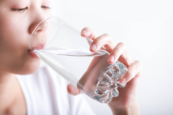 Uma jovem mulher a beber água. Modelo feminino segurando vidro em seu ha
 - Foto, Imagem