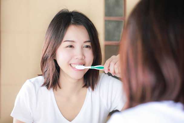 若い女性が鏡で彼女の歯をブラッシングします。覚醒後 - 写真・画像