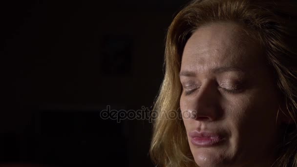 Nahaufnahme, traurige Frau auf dunklem Hintergrund. 4k, Zeitlupe - Filmmaterial, Video
