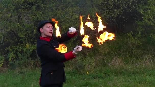 Fire Man wendingen twee verlichte Fans rond zichzelf buiten in Slo-Mo in de herfst. - Video
