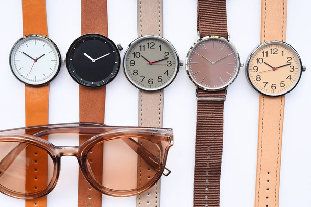 Современные модные солнцезащитные очки и набор разноцветных наручных часов изолированы на белом фоне
 - Фото, изображение
