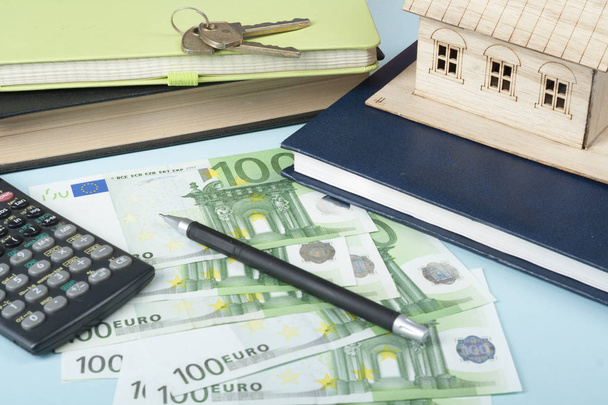 Домашні заощадження, бюджетна концепція. Модель будинку, блокнот, ручка, калькулятор і гроші на дерев'яному офісному столі
. - Фото, зображення