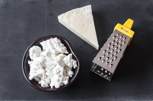 Тертый сыр пармезан и терка на деревянном фоне
 - Фото, изображение