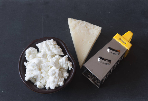 Тертый сыр пармезан и терка на деревянном фоне
 - Фото, изображение