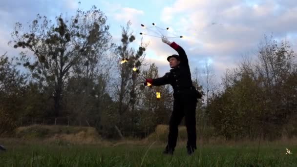 Огненный жонглер крутит два светлых вентилятора вокруг себя на улице в Сло-Мо осенью
. - Кадры, видео
