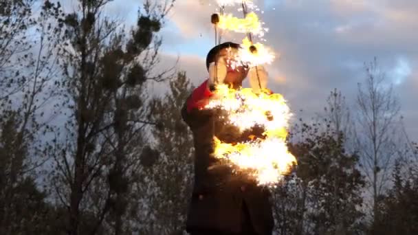 Požární muž kroutí dvě osvětlené ventilátory kolem sebe venku v Slo-Mo na podzim. - Záběry, video