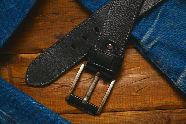 cinto de couro com fivela e jeans em fundo de madeira, vista superior
 - Foto, Imagem
