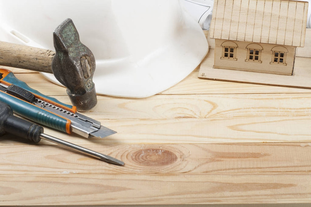 Koncepcja budowy. Modelu dom, narzędzia pracy i biały kask na podłoże drewniane. Kopiować miejsca na tekst. - Zdjęcie, obraz