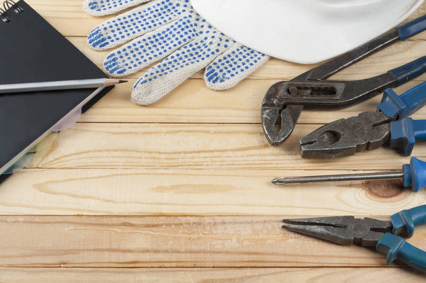Construction tools ,white helmet,notepad and work gloves on wooden background. Copy space for text. - Foto, imagen