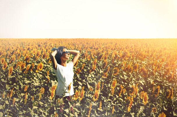 Young Beautiful Girl Standing In Sunflowers And Raising Hands Up. Freedom Lifestyle Journey Concept - Photo, Image