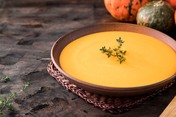Pumpkin puree soup with thyme on a dark wooden background. - Photo, Image