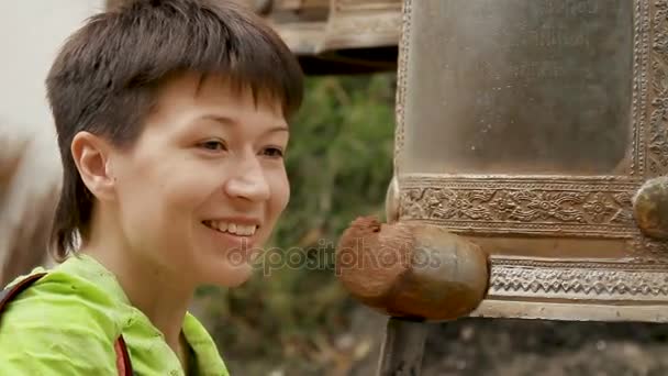 BANGKOK, THAILAND - October 24, 2012. Woman knocks on sacral bells with wooden hammer. Wat Saket Ratcha Wora Maha Wihan, the Golden Mount . - Filmagem, Vídeo