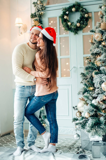 happy couple on Christmas day standing in front of the decorated tree smiling - 写真・画像