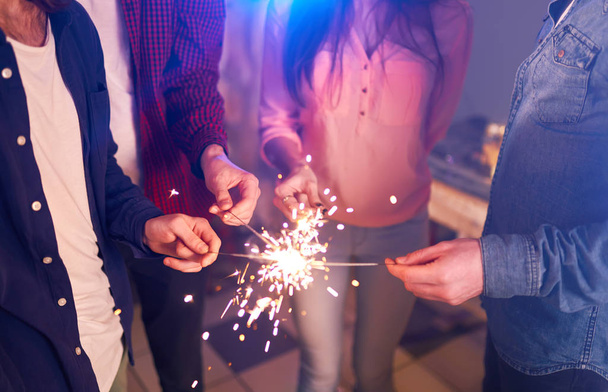 Group of friends having fun with sparklers. young people laugh. celebrating New Year together. Group of beautiful young people in Santa hats. Blur Background - Фото, зображення