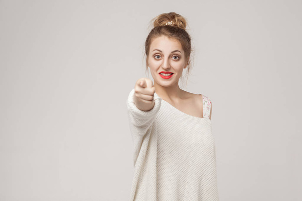Good news. Happiness blonde woman pointing finger at camera. Studio shot, isolated on gray background - Photo, Image