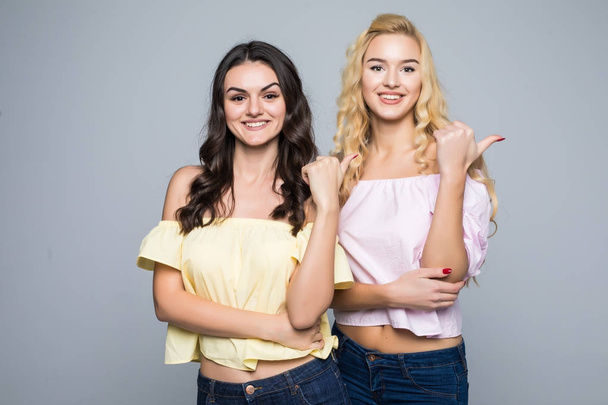 Two pretty women pointed on side over white background not isolated - Foto, afbeelding